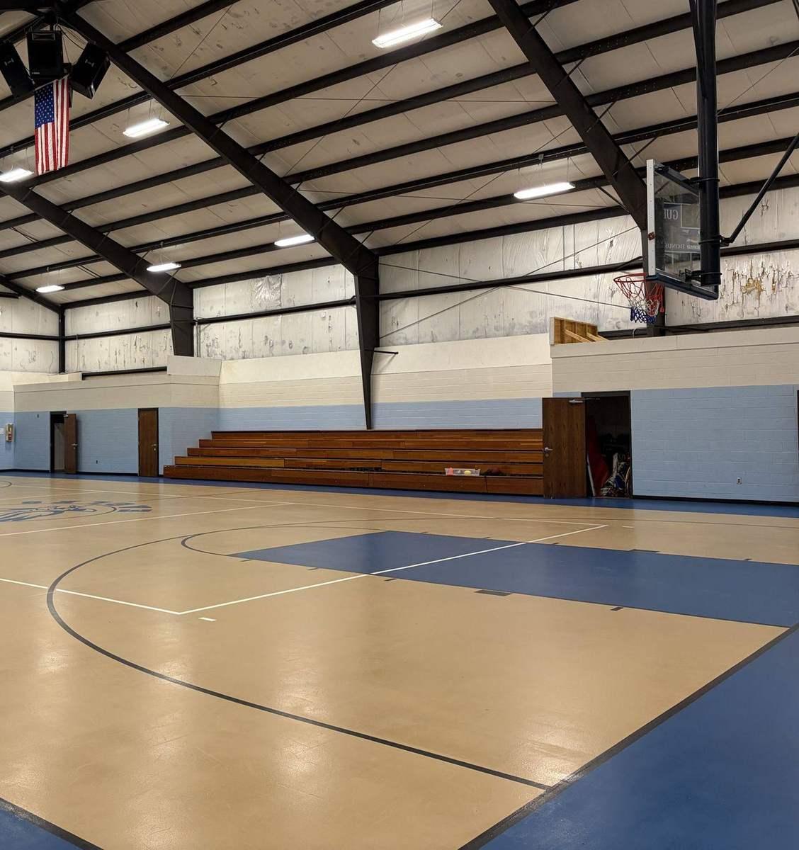 The indoor basketball court, with a wood floor, hoops and bleachers
